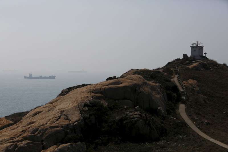 © Reuters. A ship sails past bulk carriers lying idle off the coast of Po Toi island on the southern tip of Hong Kong