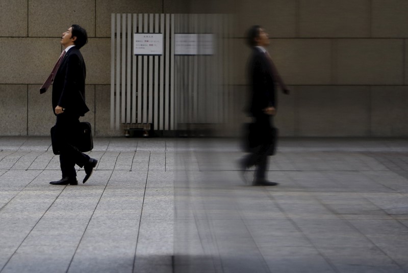 © Reuters. A man is reflected in a wall of a building at a business district in Tokyo