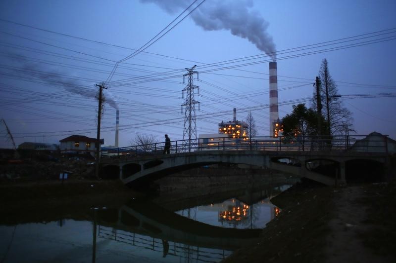 © Reuters. A man walks over a bridge as smoke rises from chimneys of a thermal power plant in Shanghai