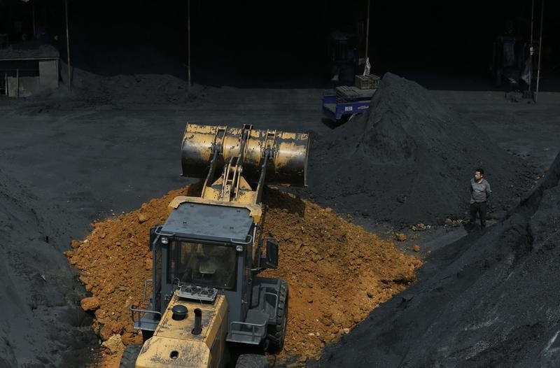 © Reuters. Man stands amidst coal at a factory in Shaoxing, Zhejiang province