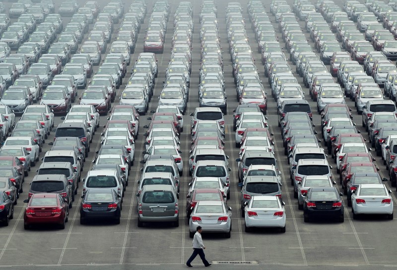 © Reuters. A man walks past a parking lot at Dayaowan port of Dalian