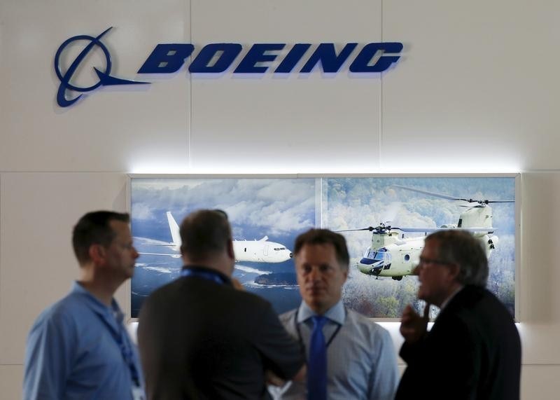 © Reuters. Visitors talk outside a Boeing booth during the opening day of the Singapore Airshow at Changi Exhibition 