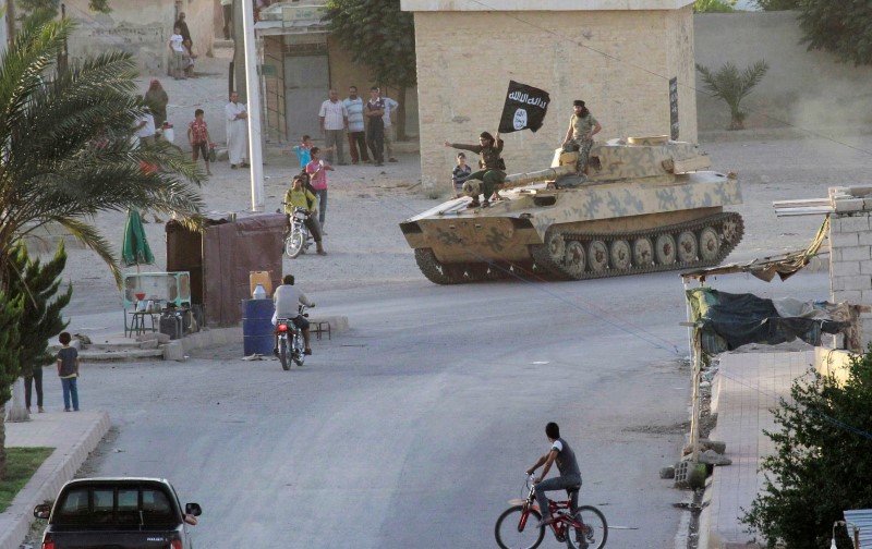 © Reuters. Residents watch militant Islamist fighters taking part in a military parade along the streets of Syria's northern Raqqa province