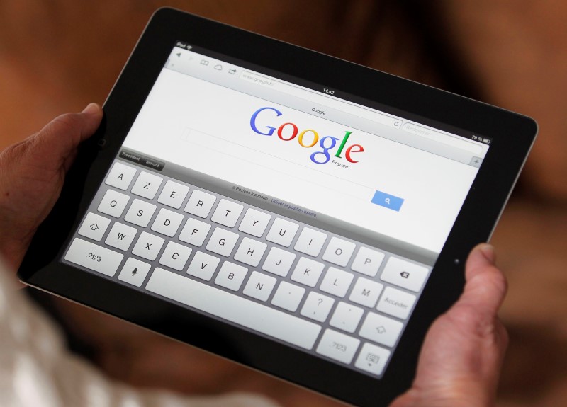 © Reuters. An illustration picture shows a woman holding her Apple Ipad which displays a tactile keyboard under the Google home page in Bordeaux