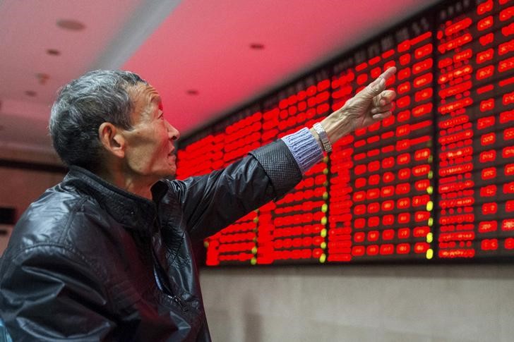 © Reuters. An investor points to an electronic board showing stock information as he speaks to another investor, at a brokerage house in Nanjing, Jiangsu province, China