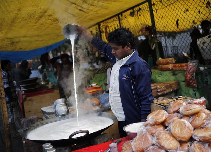 © Reuters. Торговец на рынке в Нью-Дели выливает молоко на плиту 
