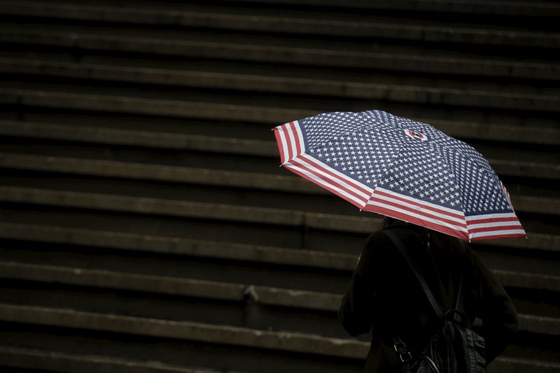 © Reuters. A tourist carries an umbrella during a rain storm on Wall St. in New York's financial district 