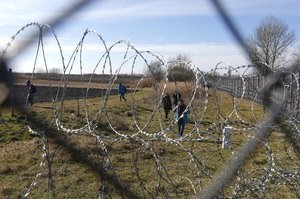 © Reuters. Migrants walk along Hungary's border fence on the Serbian side of the border near Morahalom