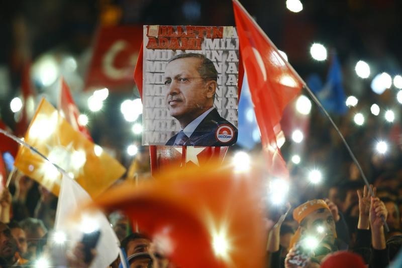 © Reuters. People wave flags and hold a portrait of Turkish President Erdogan as they wait for the arrival of Prime Minister Davutoglu in Ankara