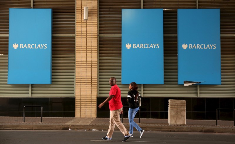 © Reuters. A couple walks past a Barclays logo in Johannesburg