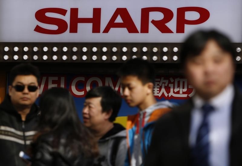 © Reuters. A logo of Sharp Corp is seen above Chinese tourists standing outside an electronics retail store in Tokyo
