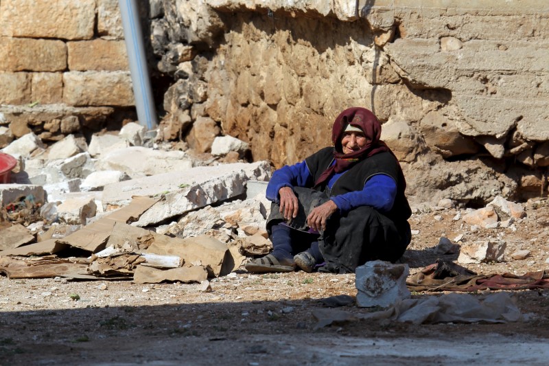 © Reuters. A women rests near rubble on the ground in the town of Darat Izza, province of Aleppo