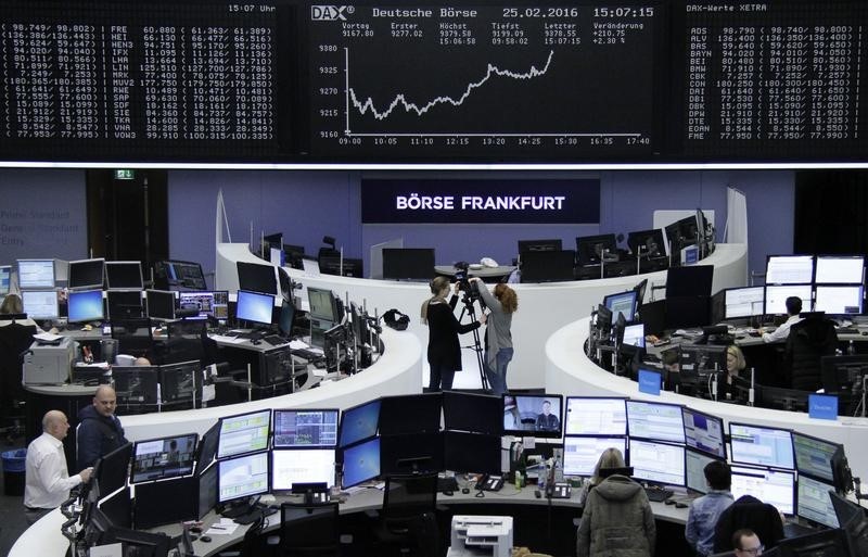 © Reuters. Traders work at their desks in front of the German share price index, DAX board, at the stock exchange in Frankfurt