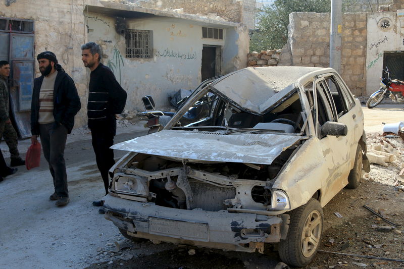 © Reuters. Residents stand near a damaged car in the town of Darat Izza, province of Aleppo