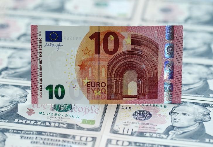 © Reuters. Una banconota da 10 euro su un "tappeto" di tagli da 10 dollari