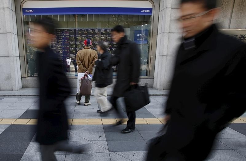 © Reuters. A pedestrian looks at various stock prices outside a brokerage in Tokyo