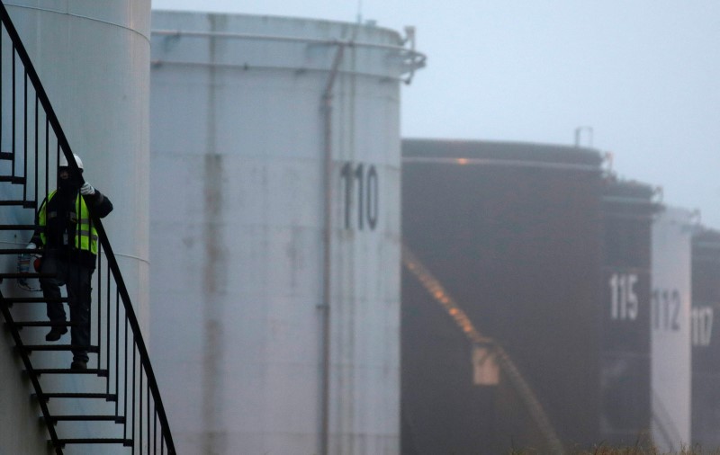 © Reuters. A worker walks up the stairs on the side of an oil tank at the Total refinery in Grandpuits