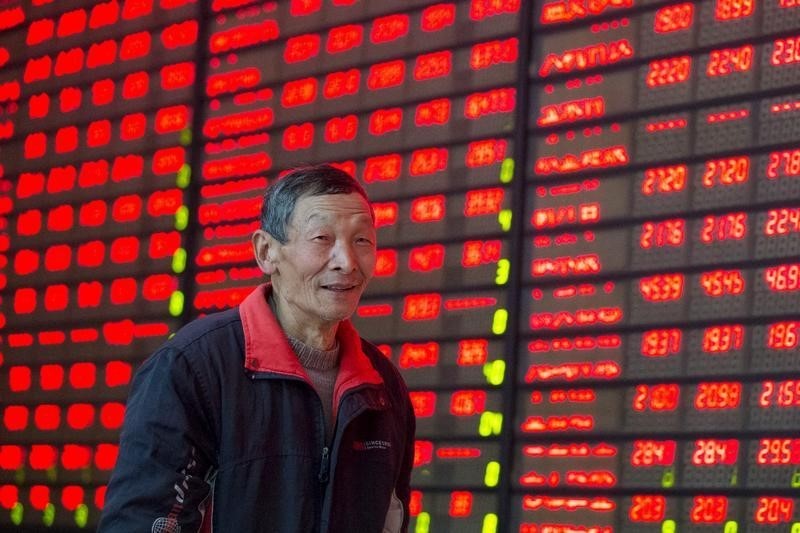 © Reuters. An investor walks past an electronic screen showing the stock information at a brokerage house in Nanajing