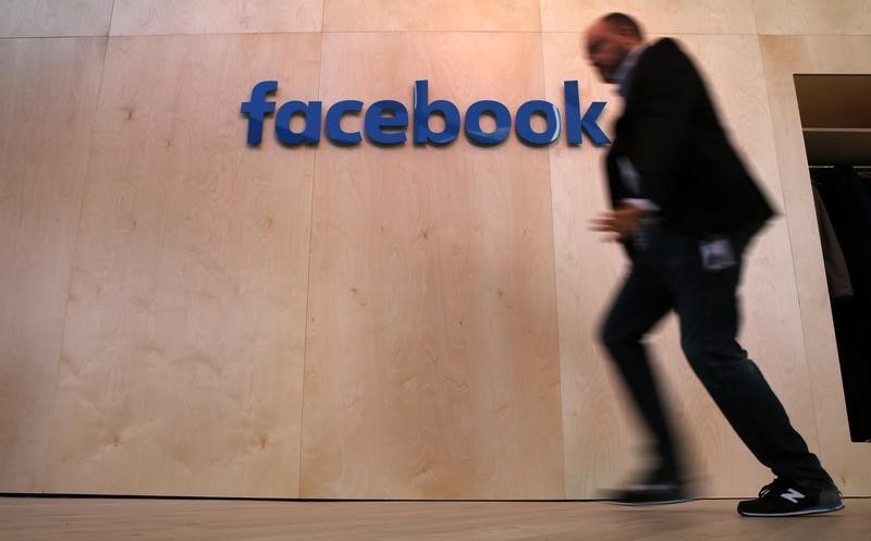 © Reuters. A man walks in front of the Facebook logo at the new Facebook Innovation Hub during a preview media tour in BerlinInnovation Hub during a preview media tour in Berlin