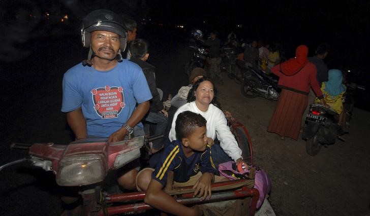 © Reuters. Residents flee to higher ground after an earthquake struck off the west coast of Sumatra, in the city of Padang, West Sumatra