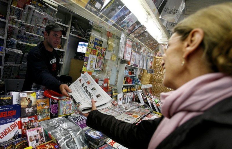 © Reuters. A woman buys a copy of Italian newspaper La Repubblica in Rome