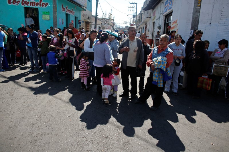 © Reuters. Residents wait in line to receive bedspreads handed out by local authorities at the main plaza of San Lorenzo Acopilco