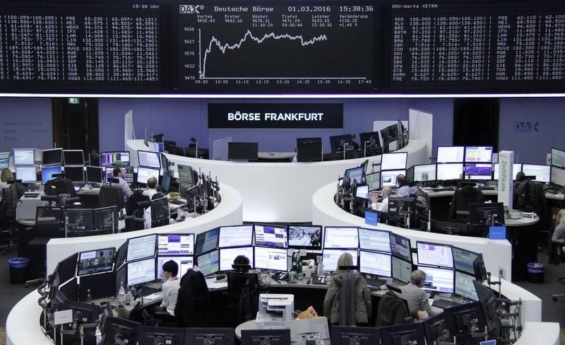 © Reuters. Traders work at their desks in front of DAX board at Frankfurt stock exchange