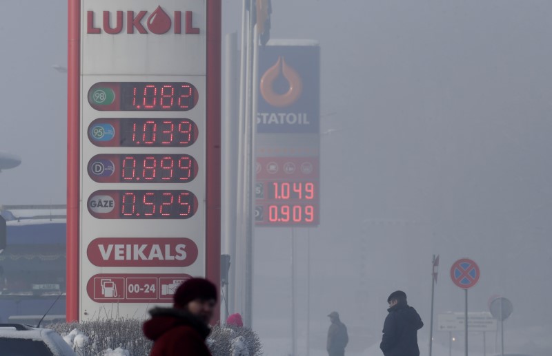 © Reuters. People walk past "Lukoil" and "Statoil" fuel stations displaying prices 1,125 USD and 1,136 USD per litre of basic unleaded petrol during a foggy winter day in Limbazi