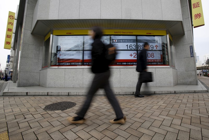 © Reuters. Pedestrians walk pass an electronic board outside a brokerage in Tokyo
