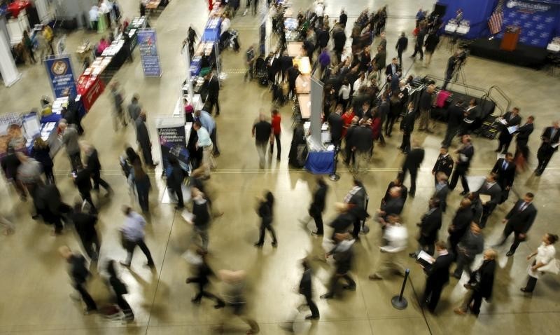© Reuters. Job seekers break out to visit employment personnel at 