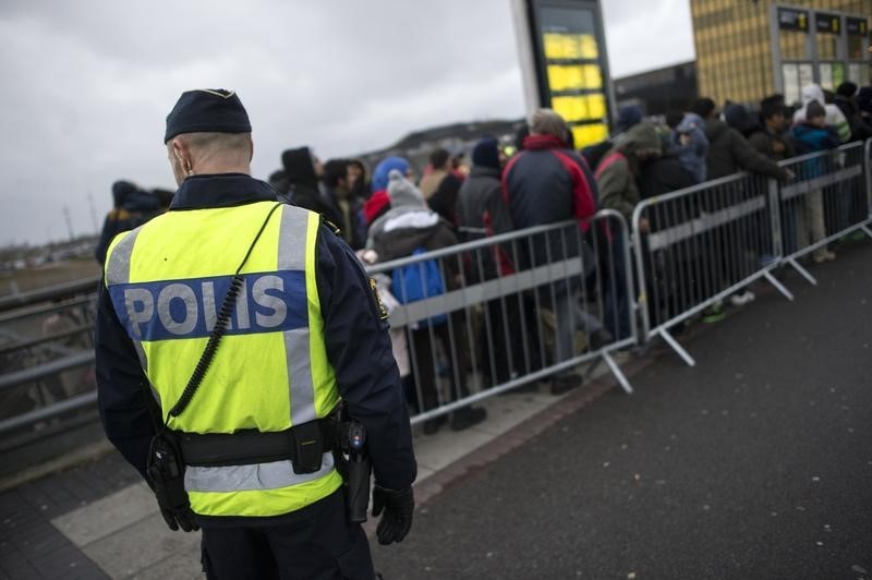 © Reuters. A police officer keeps guard as migrants arrive at Hyllie station outside Malmo