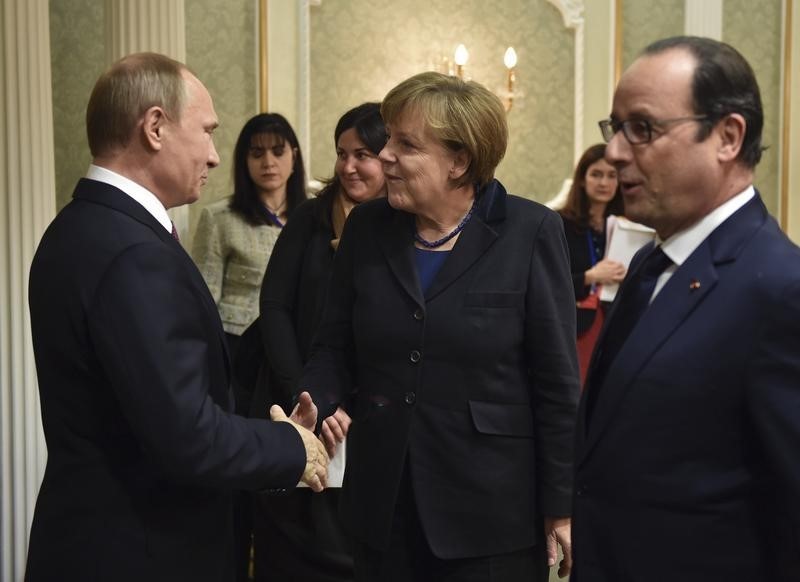 © Reuters. Il presidente russo Vladimir Putin (a sinistra) stringe la mano al cancelliere tedesco Angela Merkel, a destra il presidente francese Francois Hollande