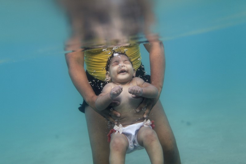 © Reuters. Rosana Vieira Alves and her 5-month-old daughter Luana Vieira, who was born with microcephaly, pose for picture in the sea of Porto de Galinhas, a beach located in Ipojuca