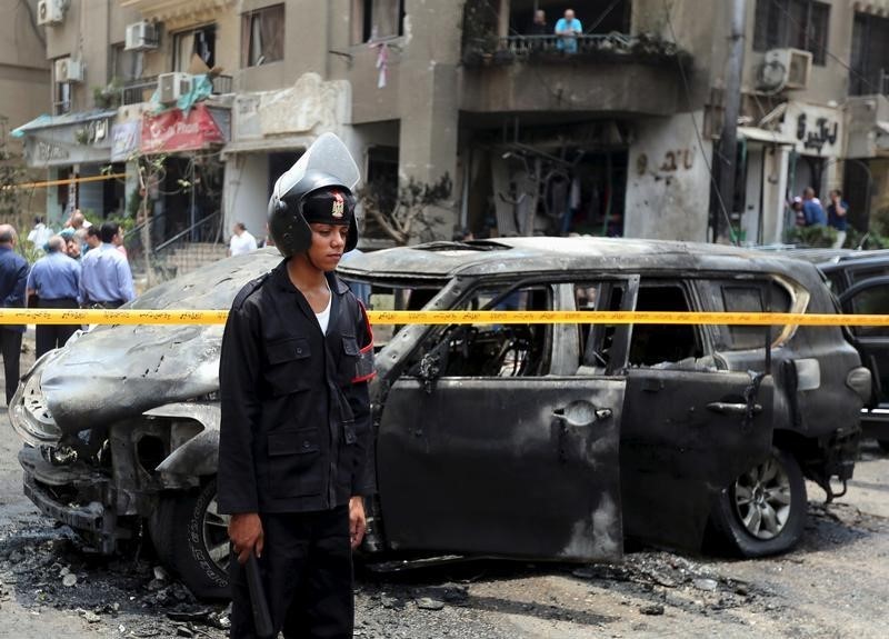 © Reuters. Policemen investigate the site of a car bomb attack on the convoy of Egyptian public prosecutor Hisham Barakat near his house at Heliopolis district in Cairo