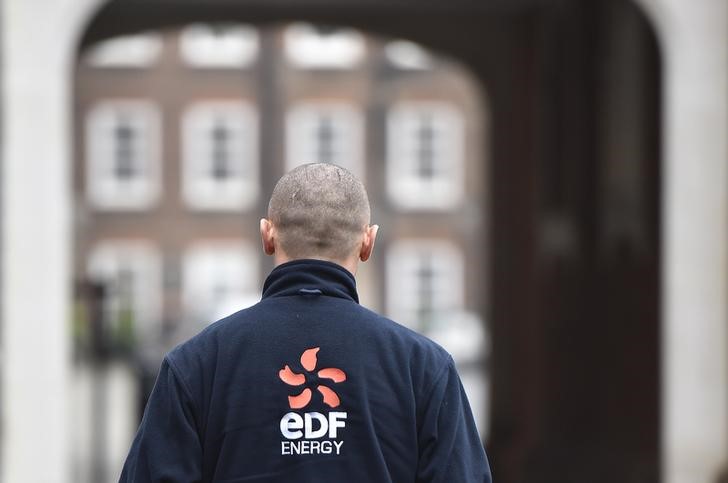 © Reuters. A worker with an EDF Energy logo on his clothing walks through an office courtyard in London, Britain