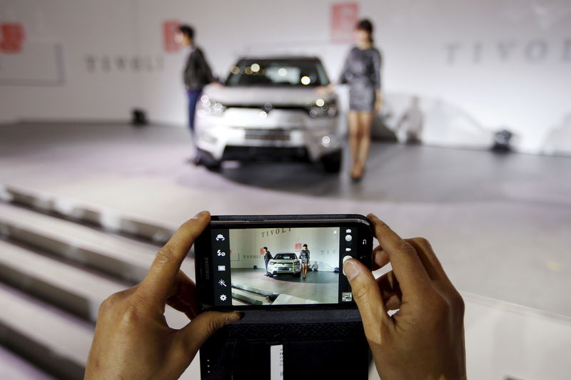 © Reuters. File photo of a man taking a photograph of Ssangyong Motor Co's Tivoli during its launch ceremony in Seoul