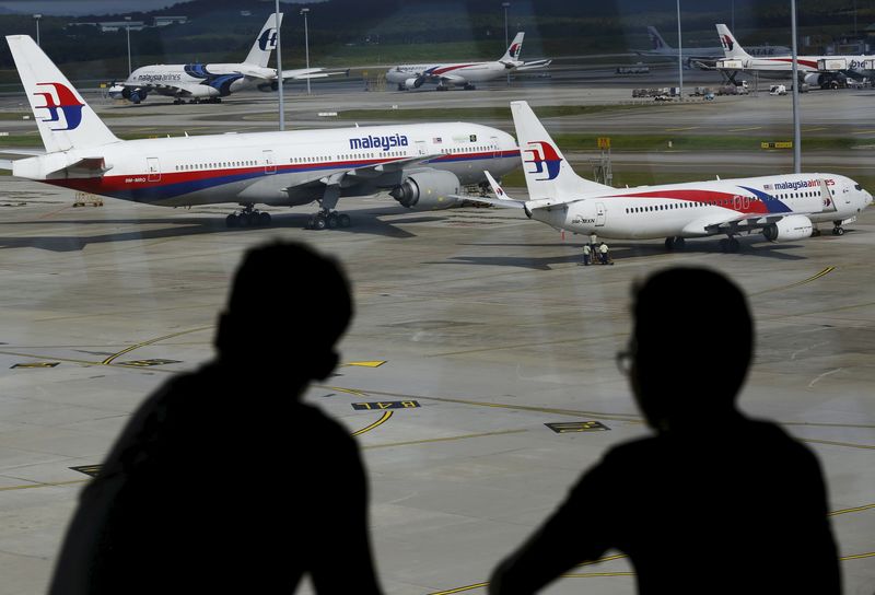 © Reuters. Men watch Malaysia Airlines aircraft at Kuala Lumpur International Airport in Sepang, Malaysia