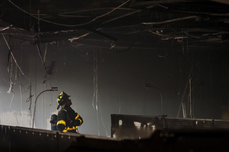 © Reuters. A firefighter looks inside a CVS pharmacy a day it was looted and set ablaze in protest for the death of 25-year-old black man Freddie Gray in Baltimore, Maryland