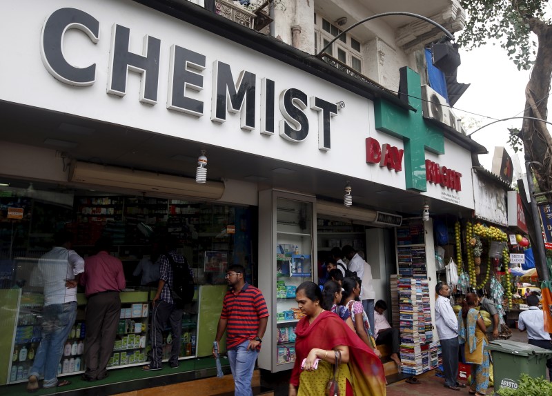 © Reuters. People walk past a chemist shop at a market in Mumbai