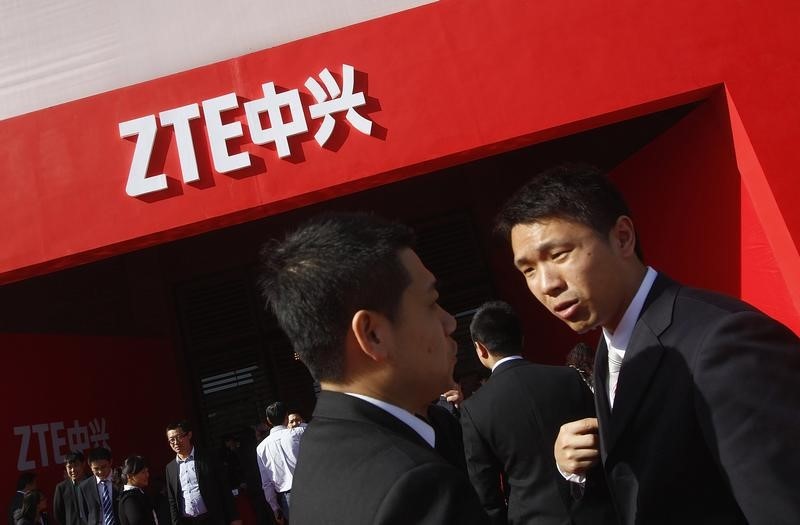 © Reuters. Guests and employees chat under a ZTE company logo in front of the venue of the company's 15th anniversary celebration in Beijing