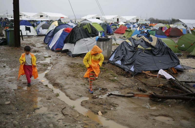 © Reuters. Imigrantes caminham em acampamento improvisado na fronteira Grécia-Macedônia