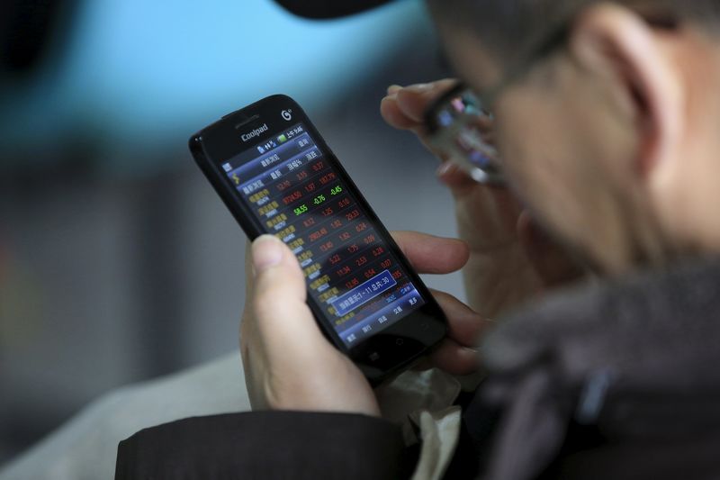 © Reuters. An investor checks stock information on a mobile phone at a brokerage house in Shanghai