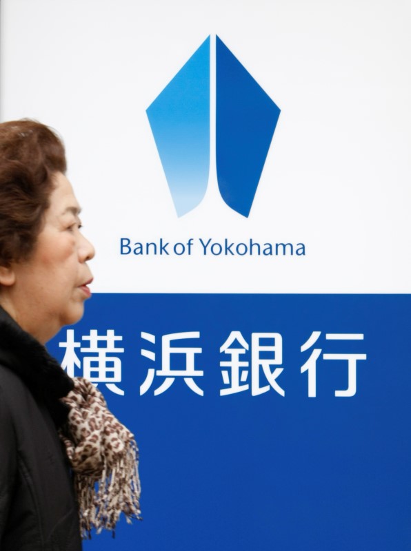 © Reuters. A woman walks past a signboard of Bank of Yokohama in Tokyo