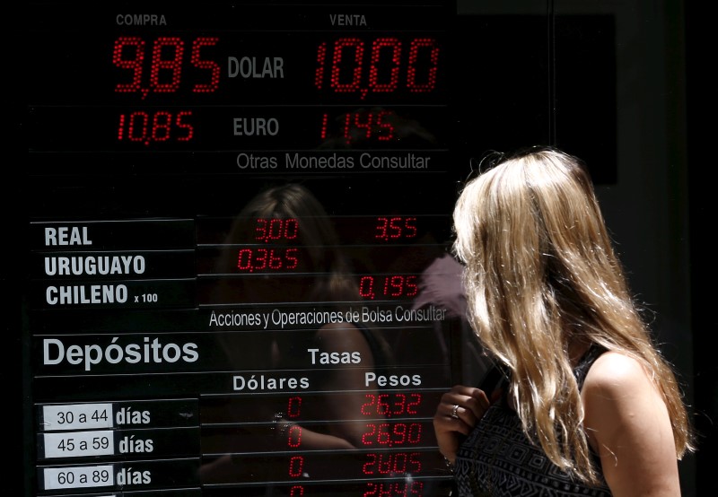 © Reuters. A woman walks past a currency exchange rates board at a money exchange in Buenos Aires' financial district