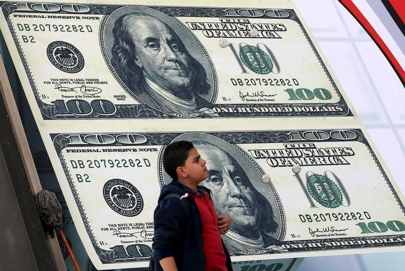 © Reuters. A boy walks past an exchange bureau advertisement showing images of the U.S dollar in Cairo