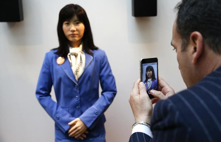 © Reuters. Visitors take pictures of communications android 'Chihira Kanae' at an information counter at ITB in Berlin