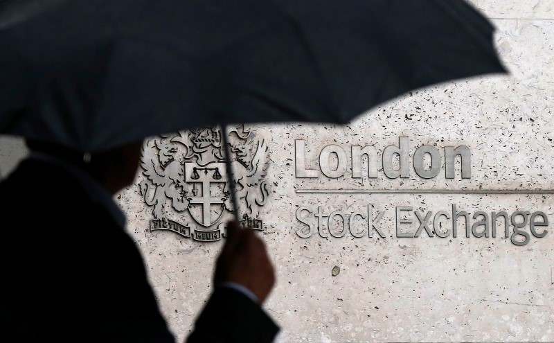 © Reuters. A man shelters under an umbrella as he walks past the London Stock Exchange 