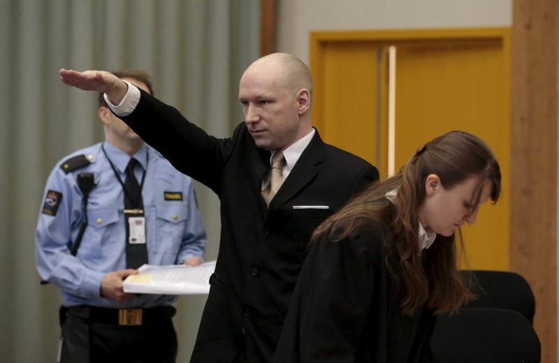 © Reuters. Mass killer Anders Behring Breivik raises his arm in a Nazi salute as he enters the court room in Skien prison