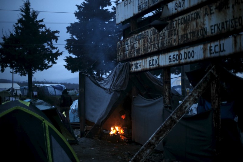 © Reuters. A migrant cooks at a bonfire inside his tent at a makeshift camp for refugees and migrants at the Greek-Macedonian border, near the village of Idomeni