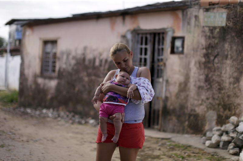 © Reuters. Gleyse da Silva segura a filha com microcefalia diante de sua casa, em Recife
